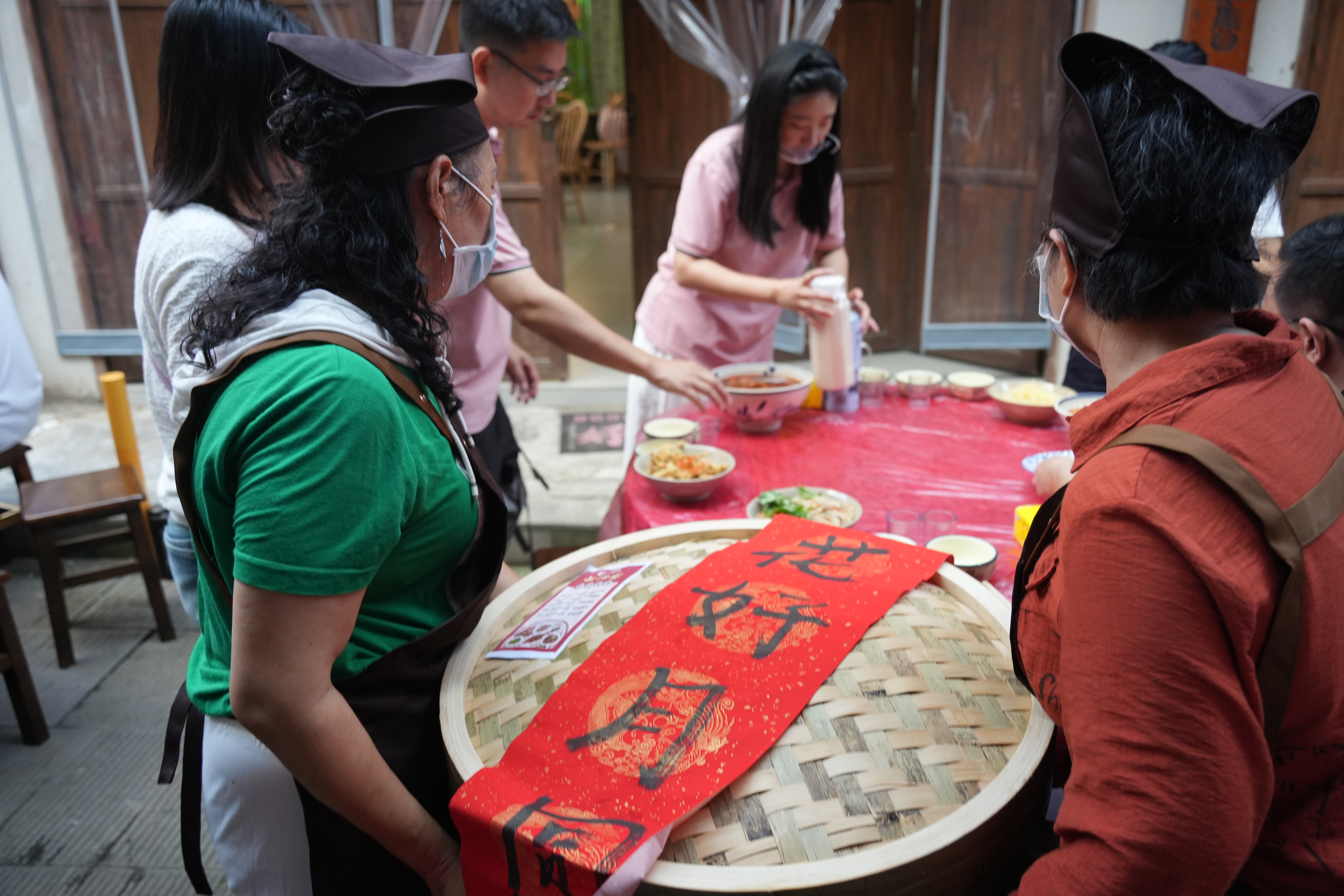 ▲商户们抬着盖有“花好月圆”字样的竹笼给游客上菜。新华社记者 田金文 摄