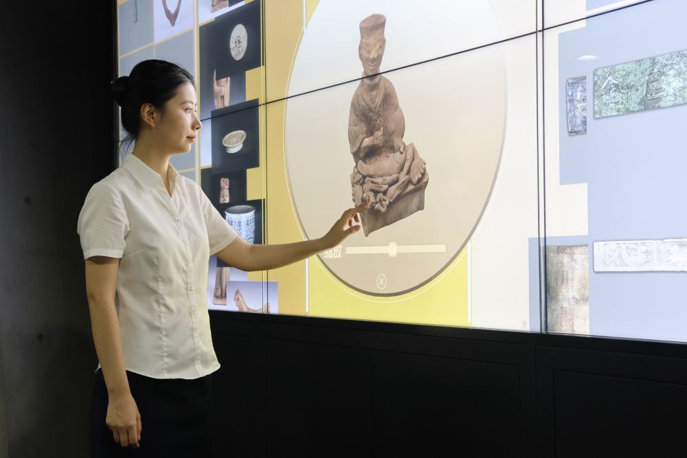 7月24日,在重庆三峡移民纪念馆,工作人员在展示用数字化呈现的藏品庖厨俑。新华社记者雷明宇 摄